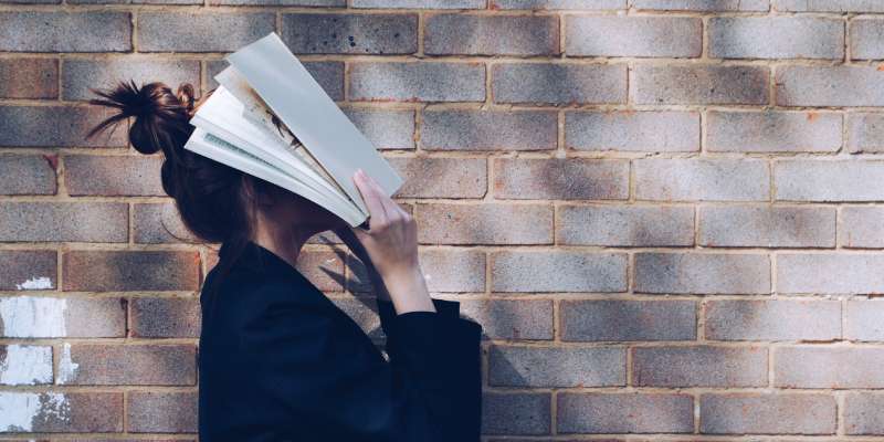 woman covering her face with a book