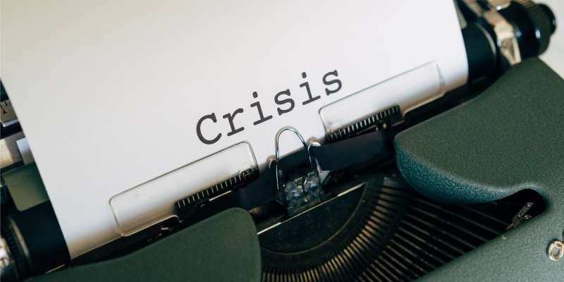 a close up of a typewriter with the word crisis typed on a sheet of paper
