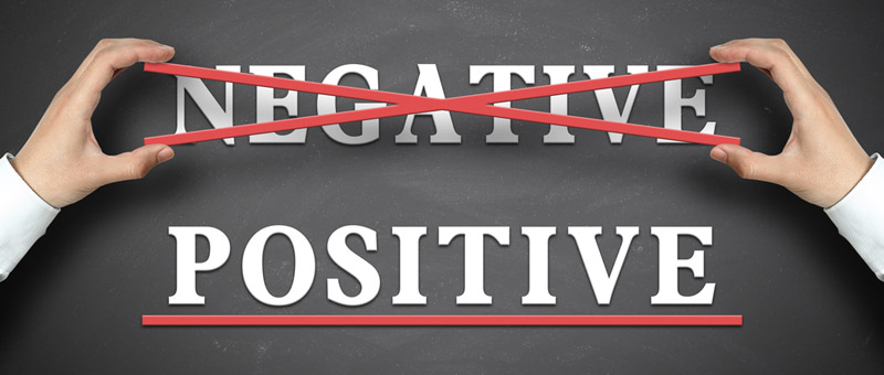 hands placing a red crooss on the word negative with the word positive below that underlined