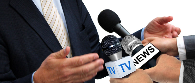 three hands holding microphones to a man in a suit