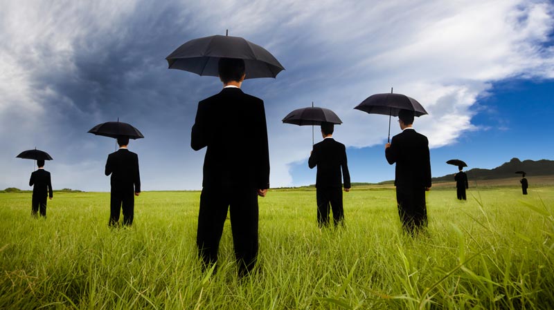 men standing in a field holding up umbrellas