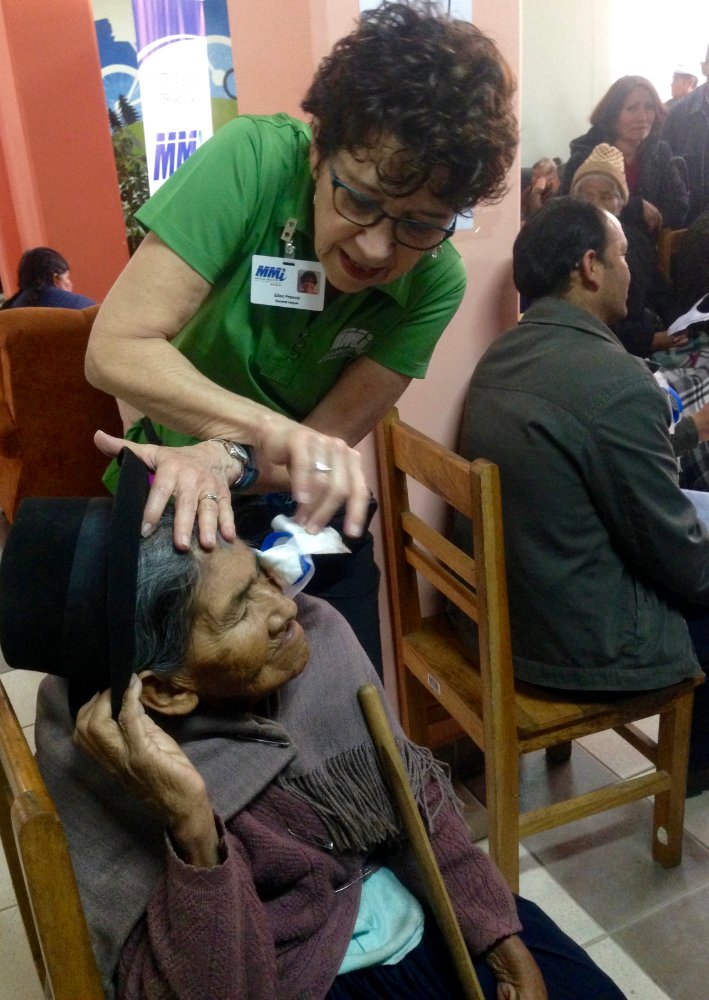 a woman pulling a bandage of an old woman's eye