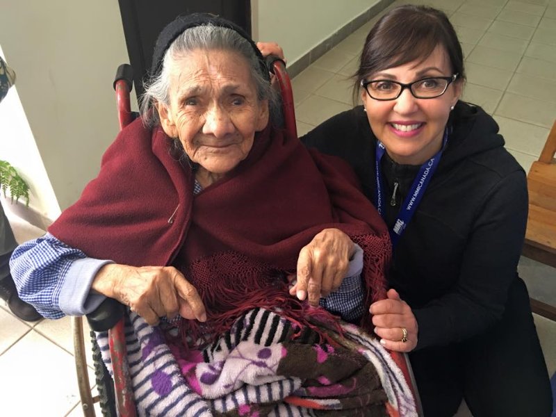 a nurse kneeling next to a woman in a wheelchair