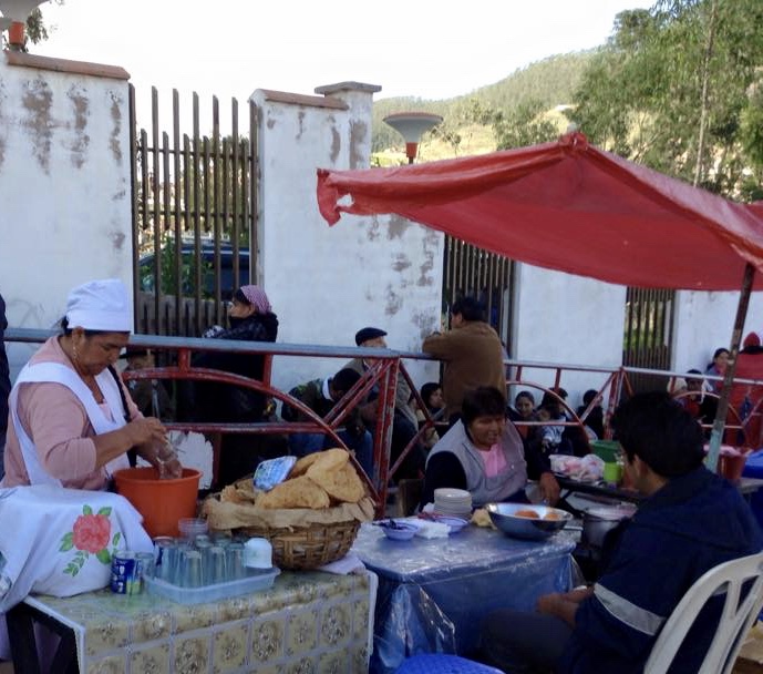 woman sitting at tables outside making tortillas