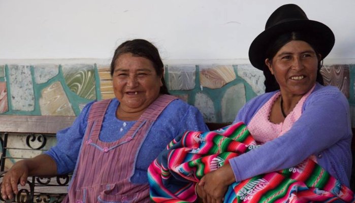 two women sitting against a wall