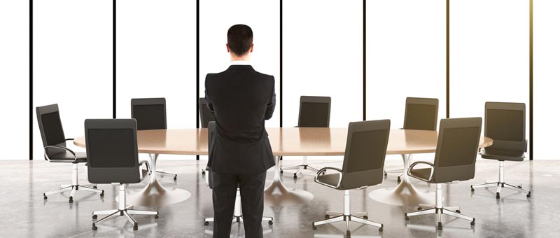 man standing at a table with empty chairs